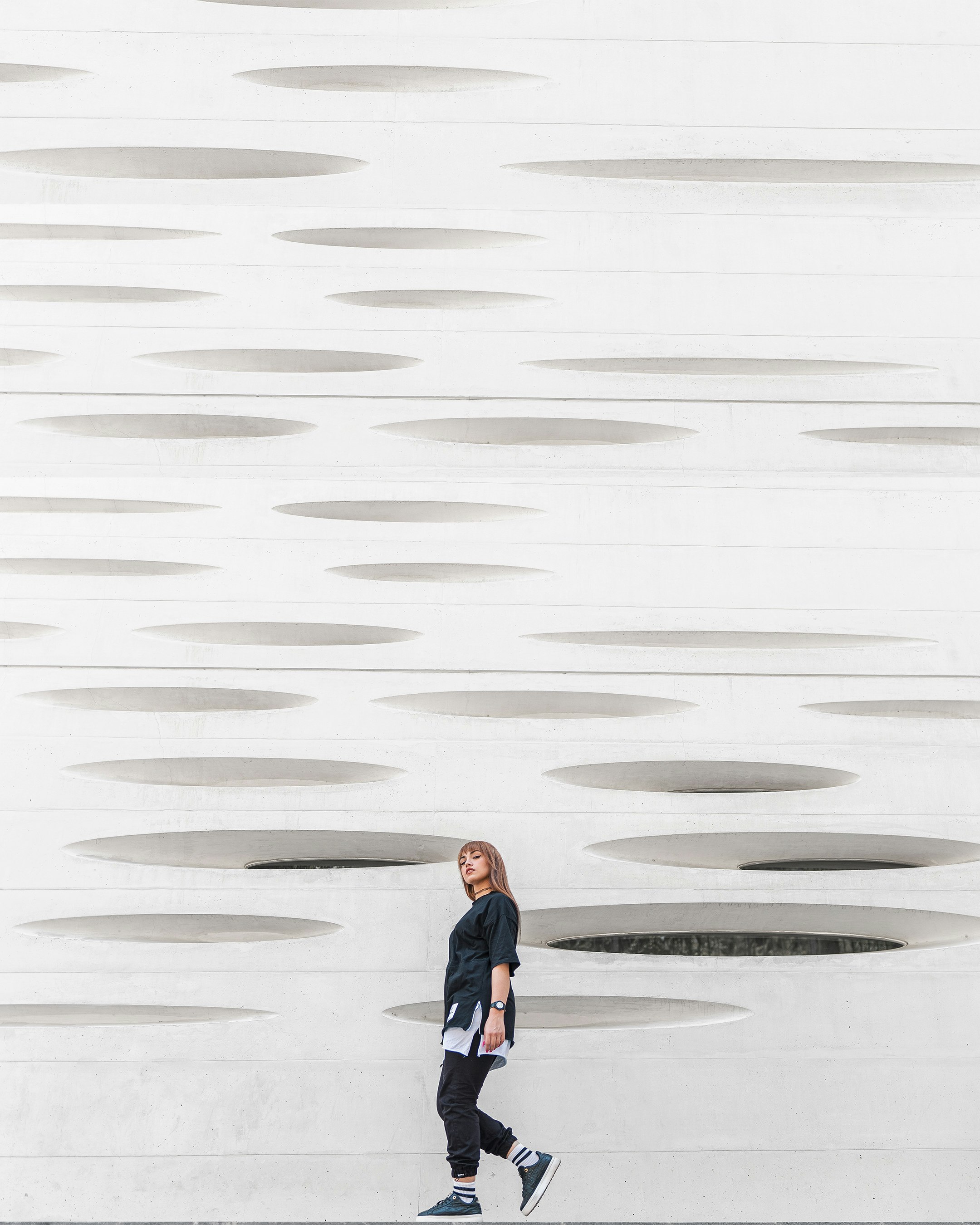 woman in blue jacket and blue denim jeans standing on white sand during daytime